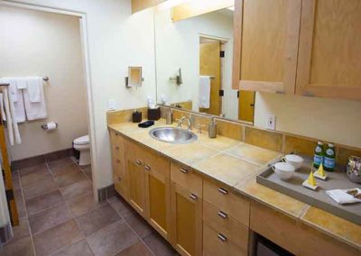 Large counter with tea and coffee, sink and mirror and toilet in separate room