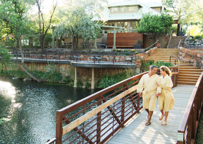 Couple walking on a brige over the pond with building in the background