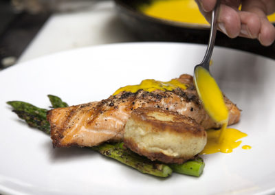 Salmon and asparagus being prepared with a yellow sauce
