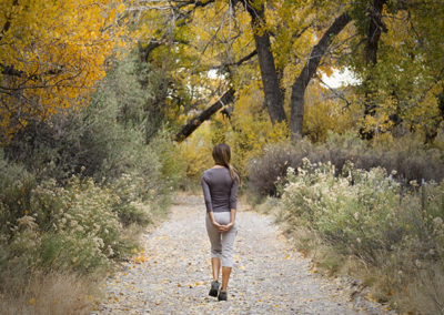 Woman walking on path under cottonwood trees