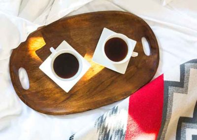 Local coffee and tea on a tray on a bed white bed with southwest blanket
