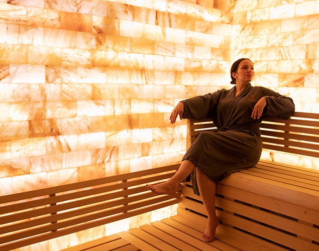 Woman in robe relaxing in pink Himalayan salt sauna