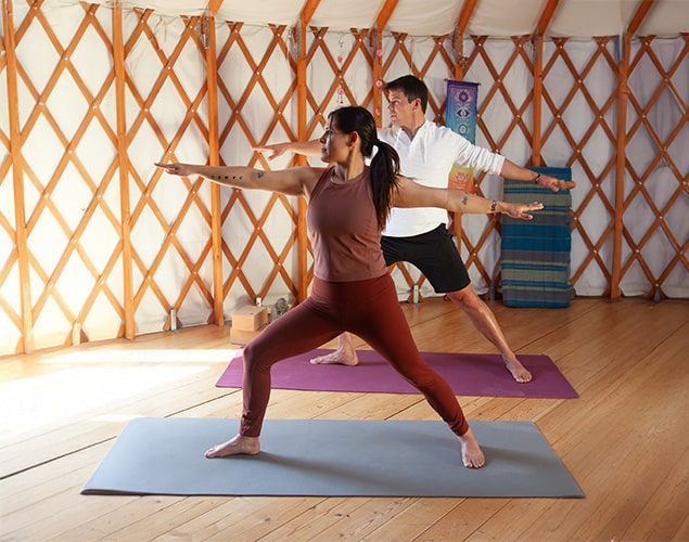 Man and woman practicing Warrior Yoga pose.