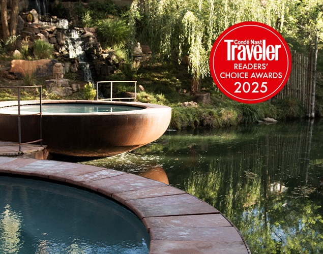 OSF_WEB_ReadersChoice_2025_635x500_02 Two round pools with stone edges overlook a tranquil pond surrounded by lush greenery. A small waterfall flows in the background. A red “Condé Nast Traveler Readers’ Choice Awards 2025” badge is displayed in the top right corner.